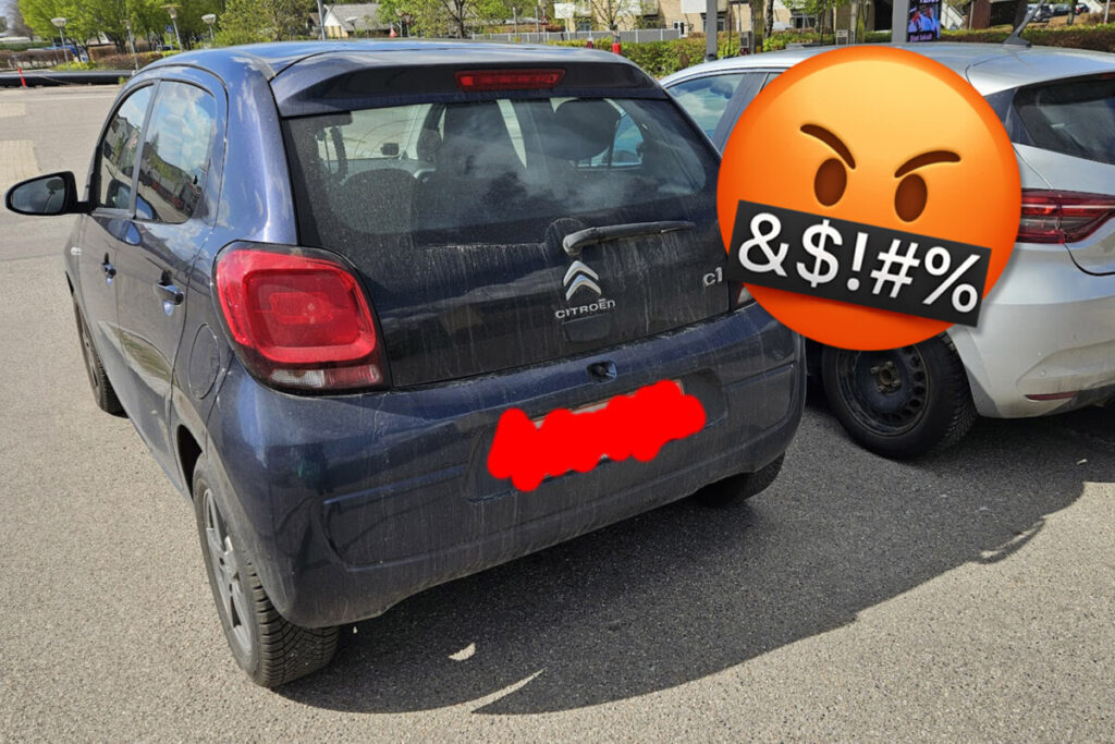 Bil med sløret nummerplade og sur smiley