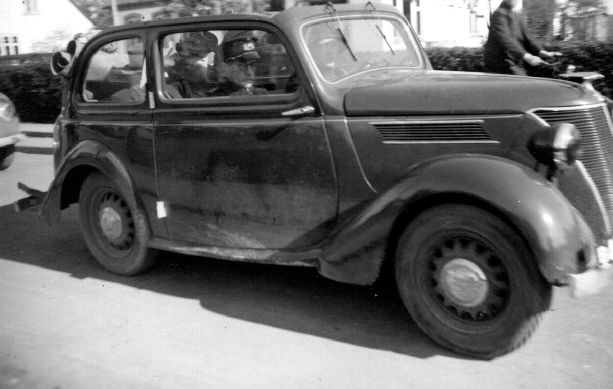 Den åbne bil med ægteparret Fiehn på bagsædet køres bort af politi og frihedskæmpere, Stenløse 9. maj 1945. Foto fra Stenløse Lokalarkiv.